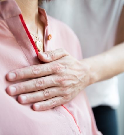 Ein Mensch legt seine Hand auf die Brust eines Patienten